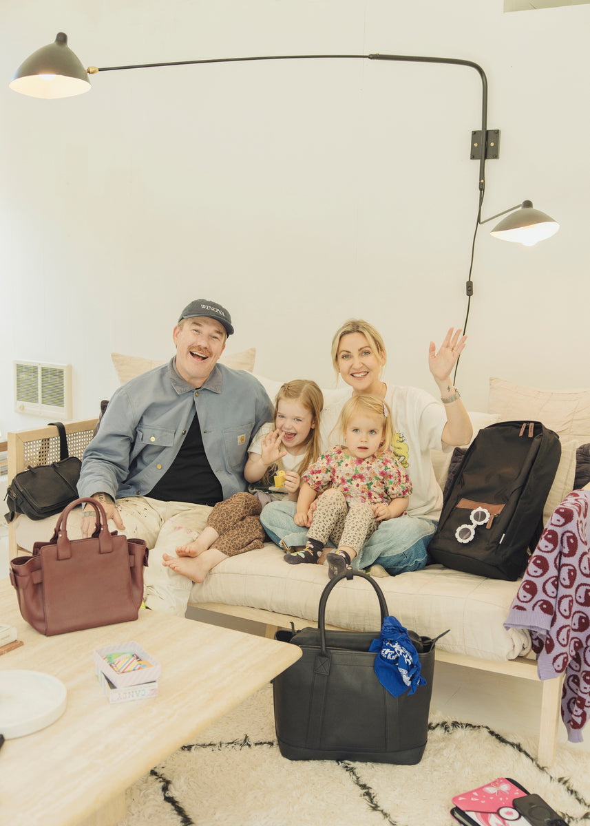 Karie Higgins and Lee Gibson with their two daughters, gathered in a modern room, smiling and enjoying their Tsuchiya Kaban leather bags together.