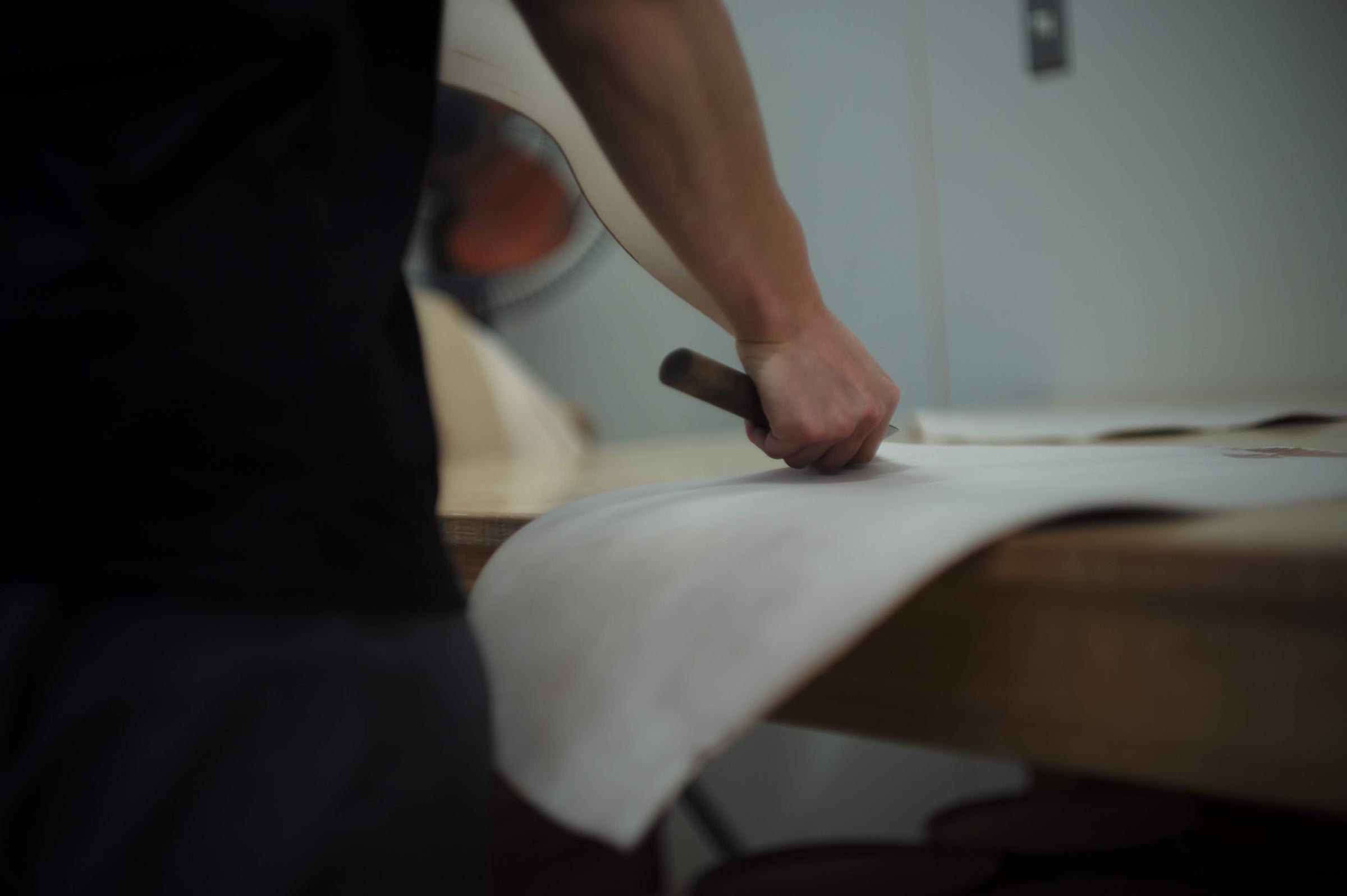 Skilled craftsman carefully cutting cordovan leather with a knife.
