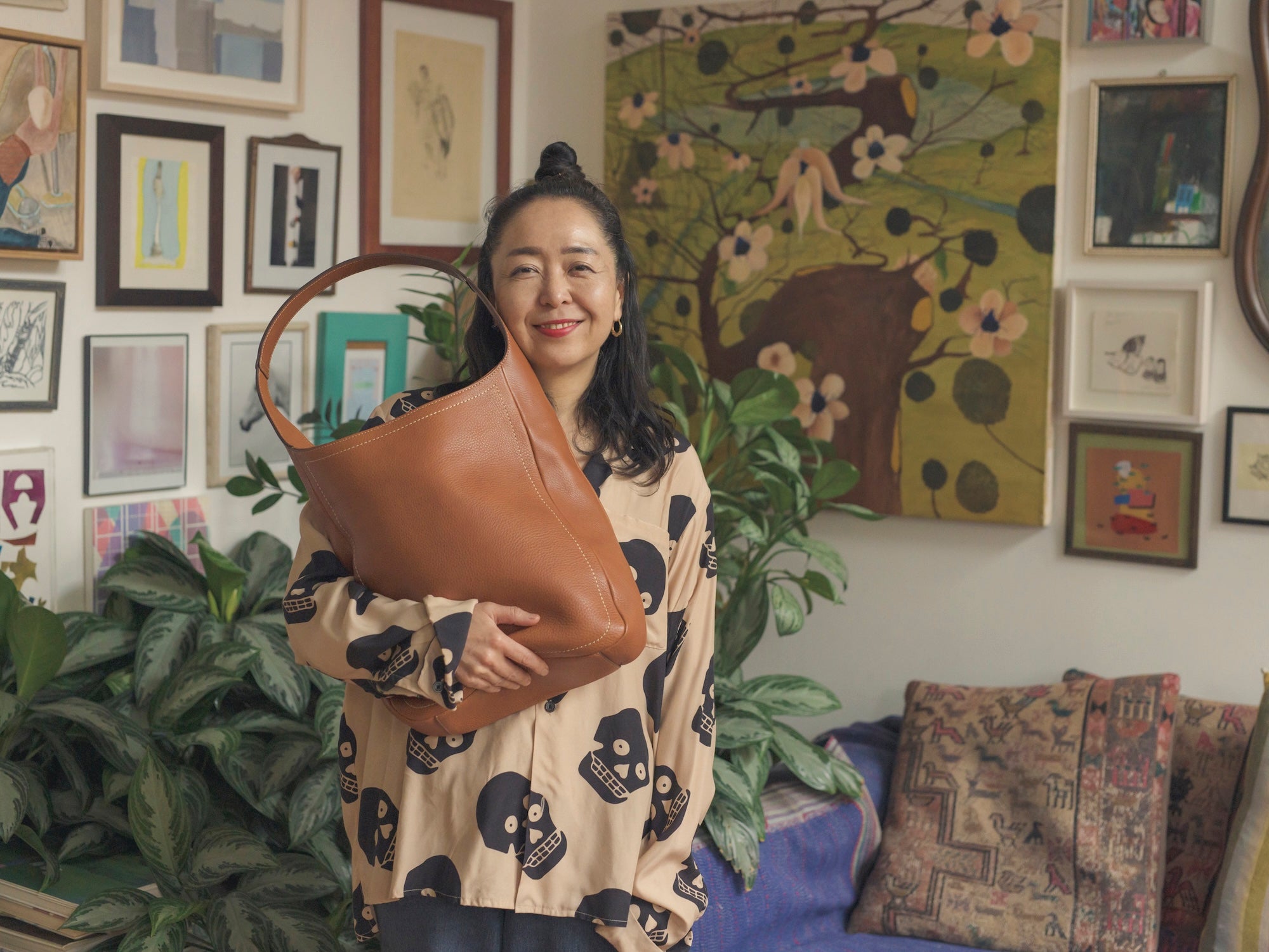 Ceramicist Shino Takeda smiling while holding her favorite Tone Nume One Shoulder Tote in Brown in her room.
