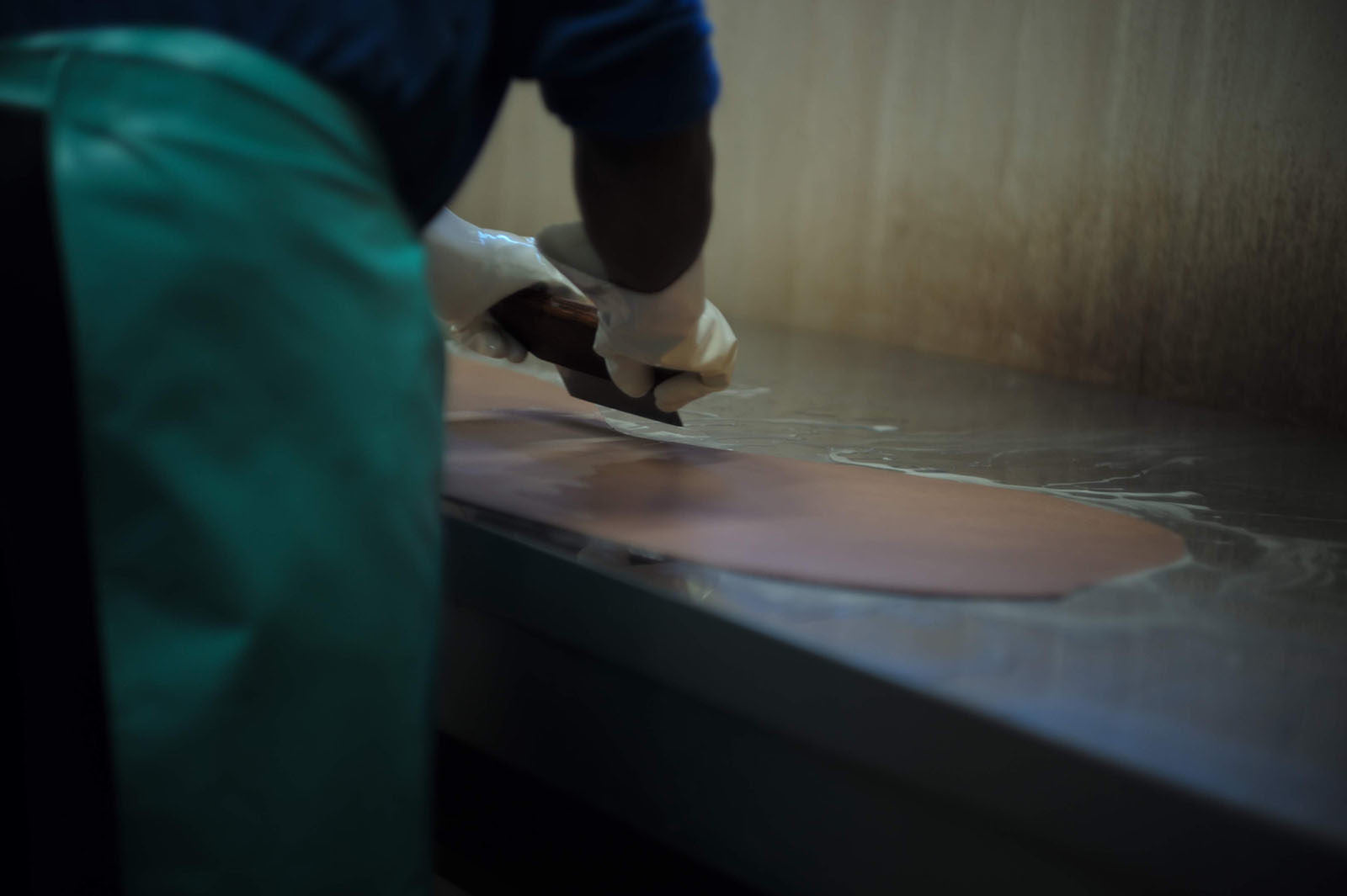 Close-up of a craftsman carefully cutting and processing glossy cordovan leather by hand.