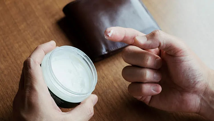 Applying leather cream to a wallet for care.
