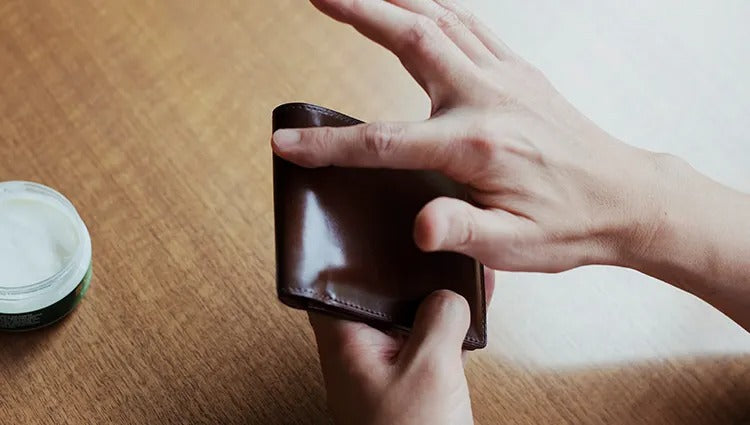 Applying leather cream to a wallet for care.