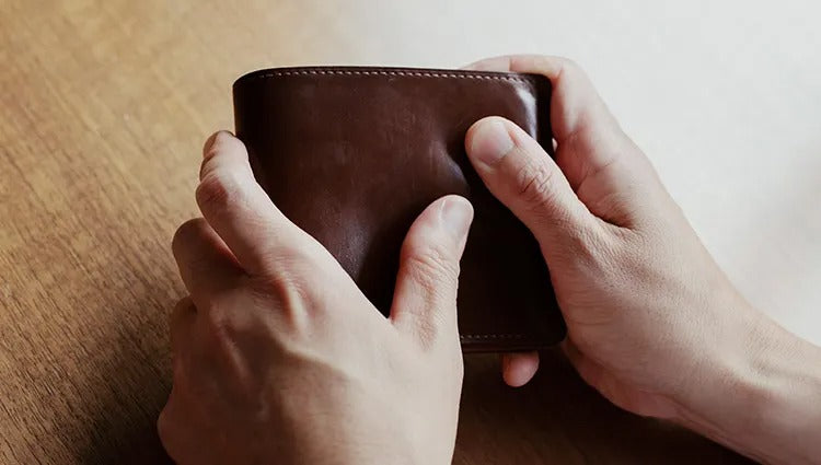 Applying leather cream to a wallet for care.